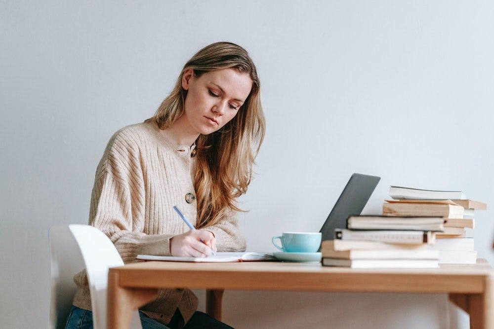 Persona leyendo y tomando apuntes para desarrollar el pensamiento crítico mediante la lectura y el aprendizaje.
