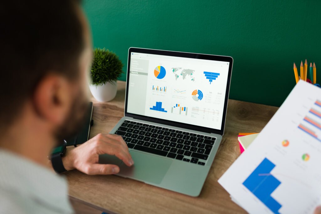 Persona analizando datos y gráficos estadísticos en un ordenador portátil para interpretar resultados empresariales.